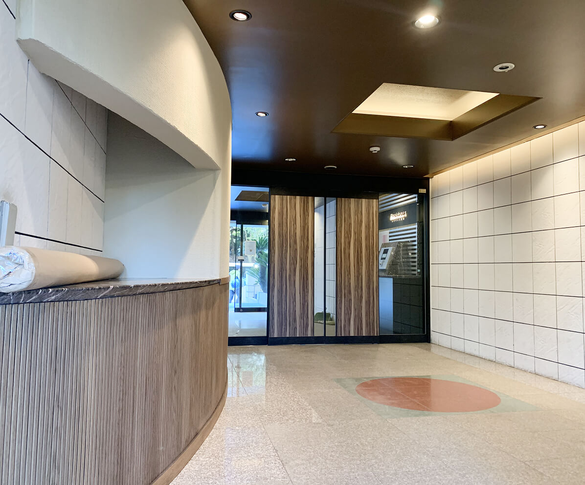 木製扉と白いタイル壁が調和したモダンなエントランス。