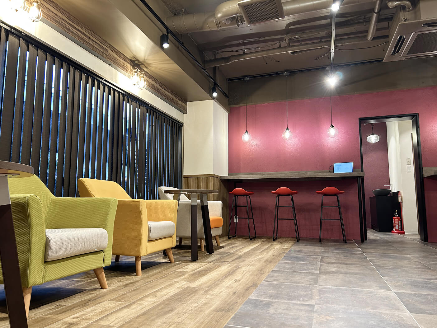 黄色や緑の椅子とボルドーの壁が印象的なモダンな室内