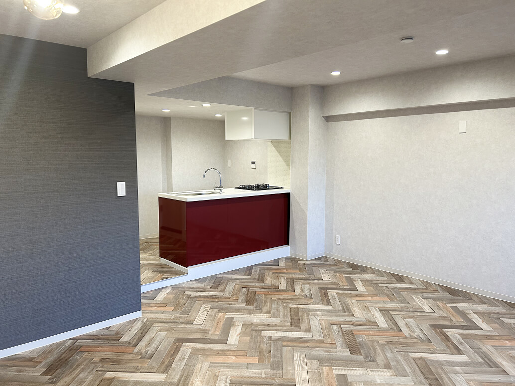 赤いパネルのキッチンとヘリンボーン柄の床がある室内