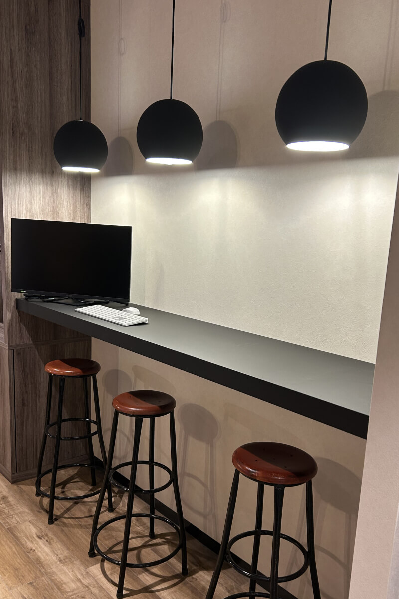 黒いカウンターにPCと丸椅子が並ぶワークスペース