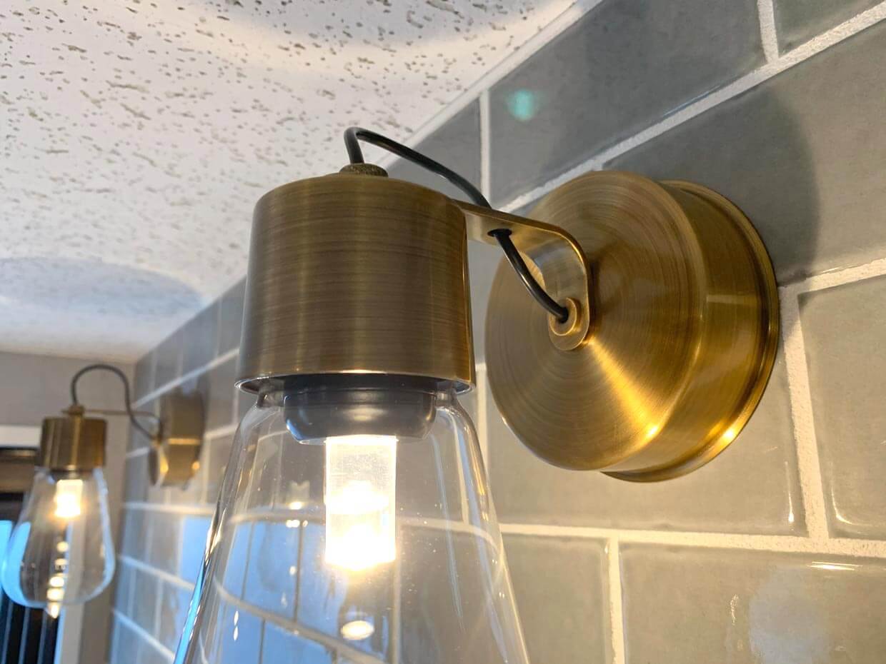 真鍮のブラケットライト： タイル壁に取り付けられた、アンティーク調の真鍮製照明器具。