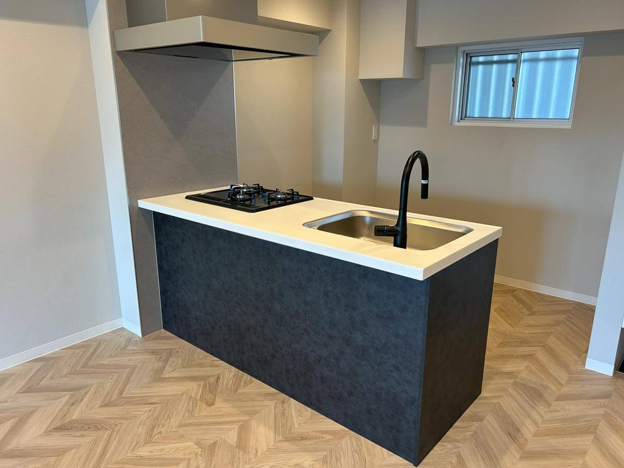 アイランドキッチン： 黒い腰壁に白い天板を組み合わせたモダンな対面キッチン。