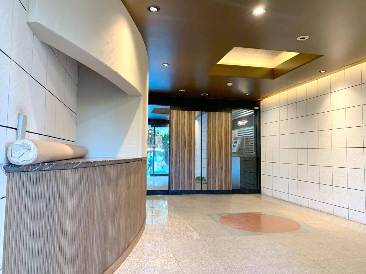 木製扉と白いタイル壁が調和したモダンなエントランス。