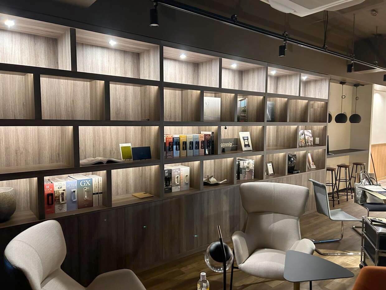 カタログや小物が整然と並ぶ、照明付きの大きな木製壁面収納。