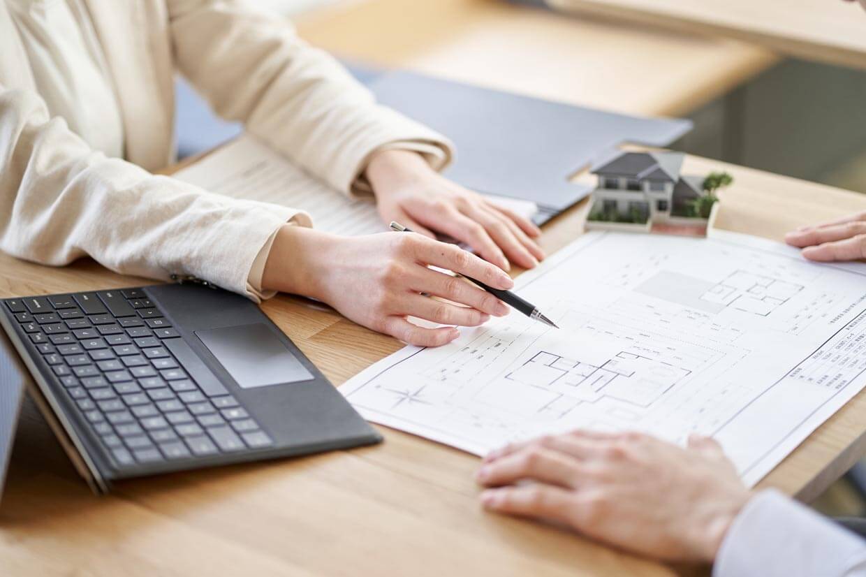 素材と図面： サンプル資料やタブレットを並べ、図面を前に打ち合わせる様子。